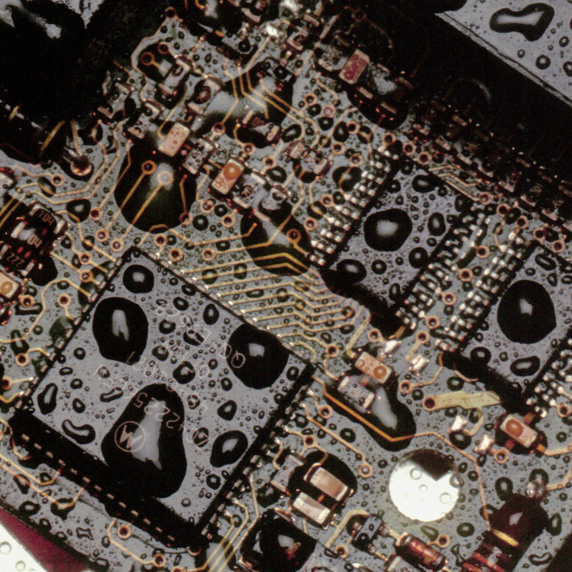 Nahaufnahme einer Leiterplatte mit Wassertropfen. Feuchtigkeit kann durch Umwelteinflüsse in die Baugruppe eindringen und Schäden verursachen.