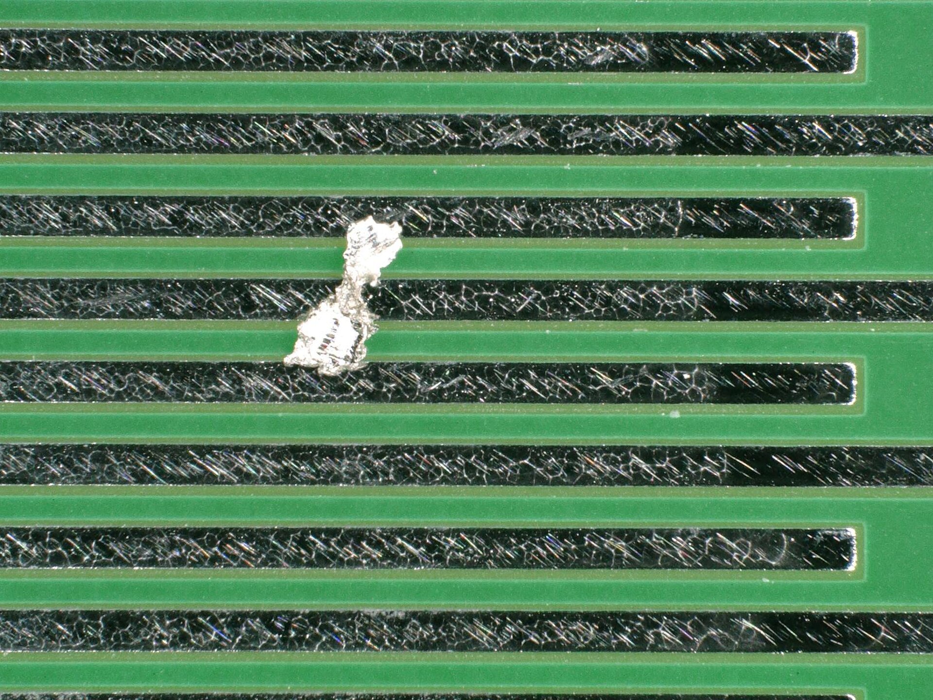 Metallisch-glänzender Partikel auf Leiterplatte – Gefahr partikelbedingter elektrischer Ausfälle | © @ZESTRON