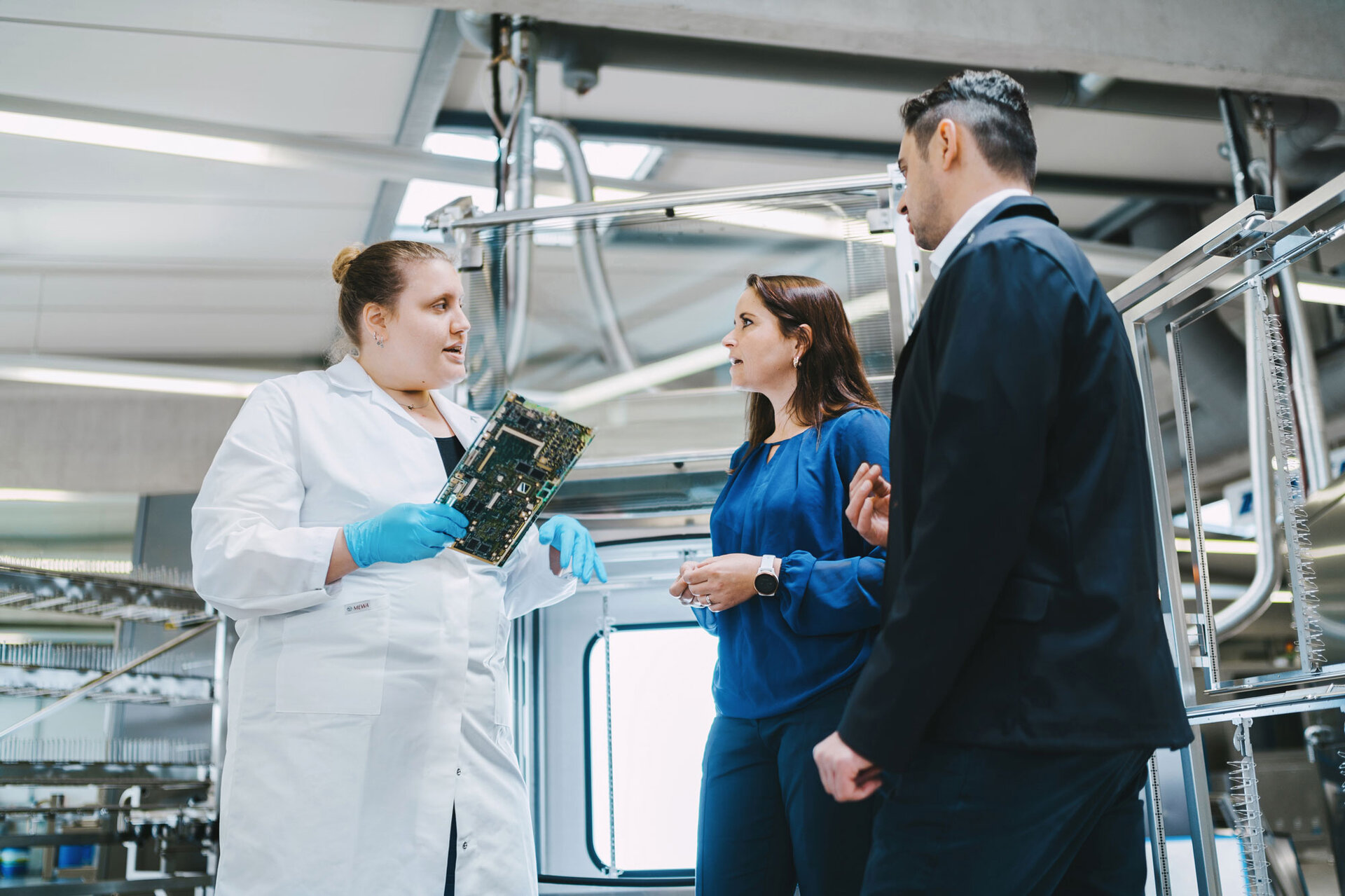 Inżynier doradza dwóm klientom w zakresie procesu czyszczenia podzespołów elektronicznych. | © @The Sour Cherry Fotografie - Michaela Curtis