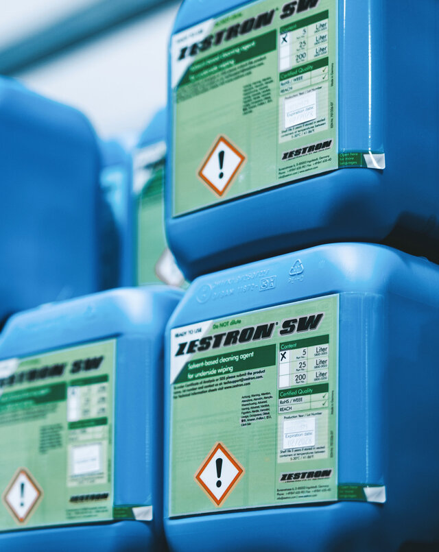 Kanistry z produktami do czyszczenia PCB firmy Zestron ułożone jeden na drugim. | © @The Sour Cherry Fotografie - Michaela Curtis