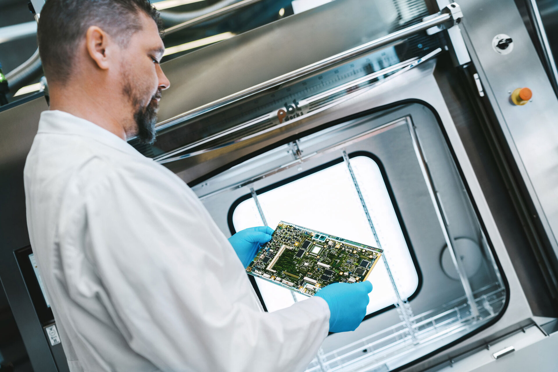 Pracownik bada płytkę drukowaną w centrum technicznym ZESTRON w celu oceny zrównoważonego procesu czyszczenia elektroniki. | © @The Sour Cherry Fotografie - Michaela Curtis