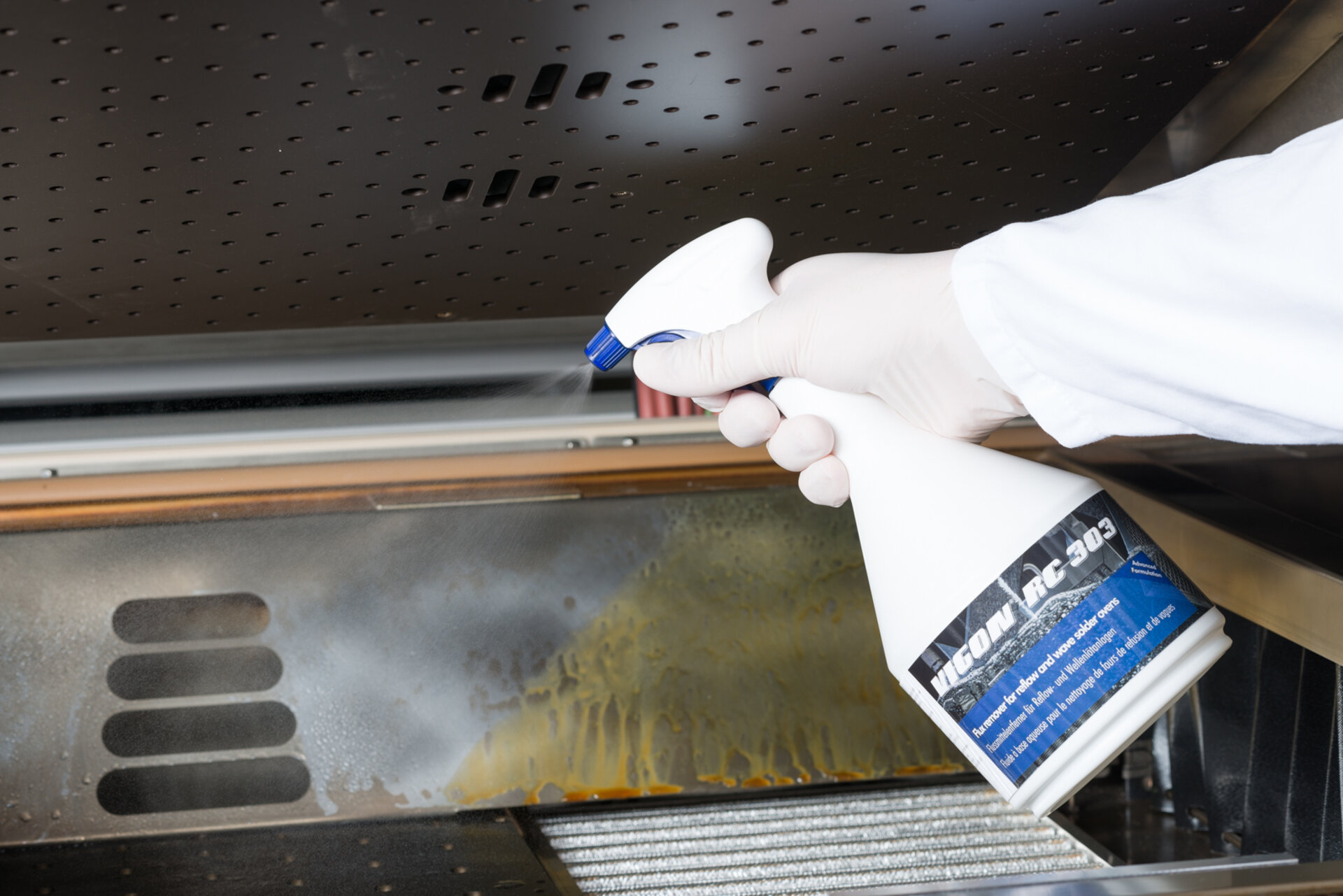 Vigon RC 303 wird auf eine Oberfläche von einer Reflowanlagen gesprüht. Eine saubere und verschmutzte Oberflächenseite werden gezeigt. | © Zestron