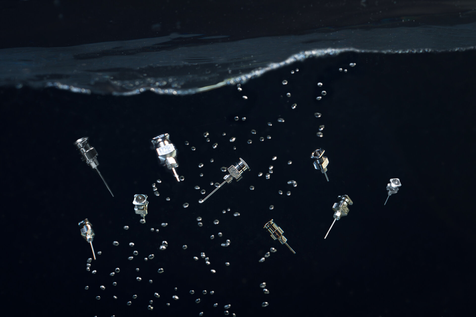 Dosiernadeln im Wasser schwebend, um deren Reinigung von Epoxykleber zu visualisieren. | © Zestron