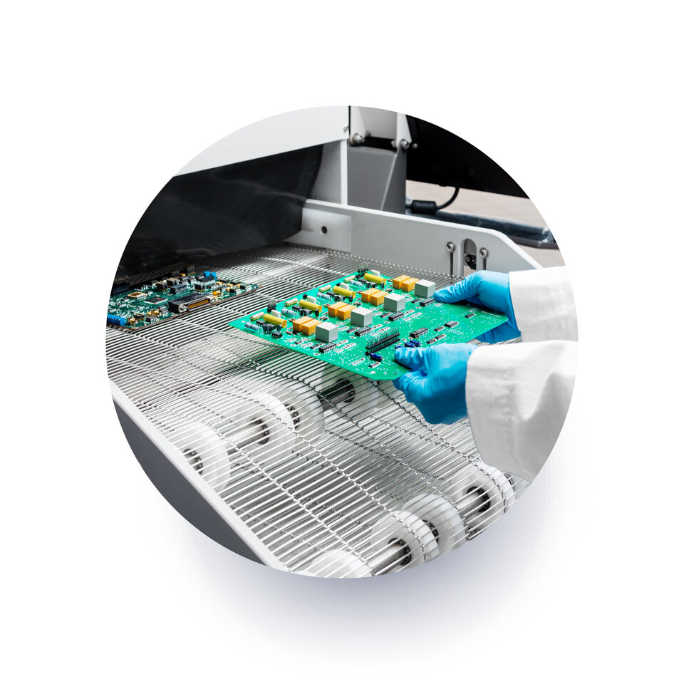 engineer putting a circuit board into a inline cleaning machine  