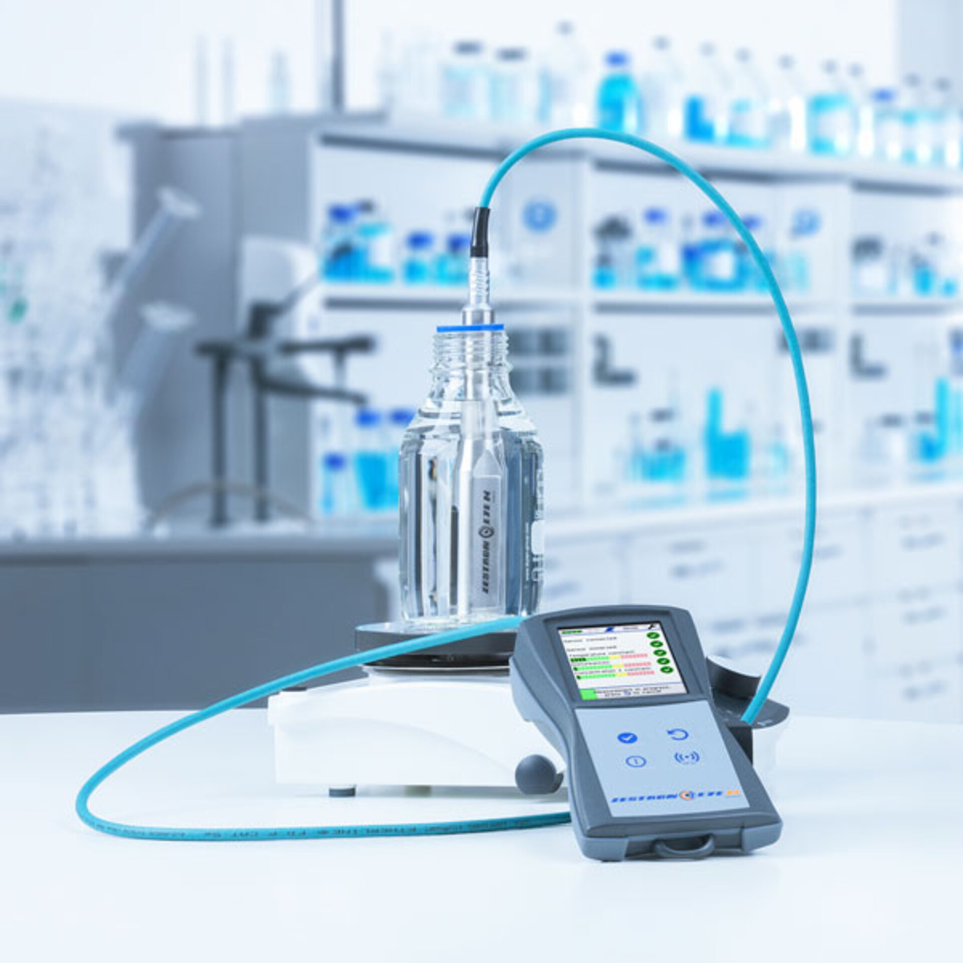 Das ZESTRON EYE Mobile ist im Vordergrund des Bildes zu sehen. Es ermöglicht mobile Konzentrationsmessung zur Überwachung des Reinigungsprozesses. Ein Labor ist im Hintergrund zu sehen. | © @Zestron